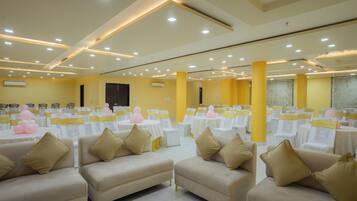 A banquet hall with round tables, chairs, and sofas arranged for an event.