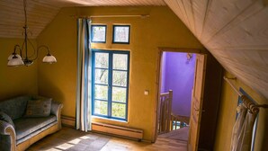 A cozy room with a large window, a wooden ceiling, and a blue sofa. - Cozy apartment with colored clay plaster, forest-quiet site (Prerow)