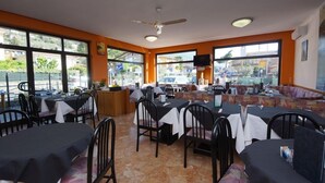 Een restaurant met tafels, stoelen, een balie en grote ramen met uitzicht op de straat.