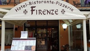 De ingang van Hotel-Ristorante-Pizzeria Firenze met een menukaart buiten.