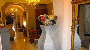 Un couloir avec un grand miroir, un vase rempli de fleurs et un lustre.