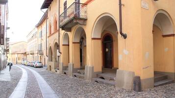 Una hilera de edificios amarillos con puertas en arco y una calle empedrada.