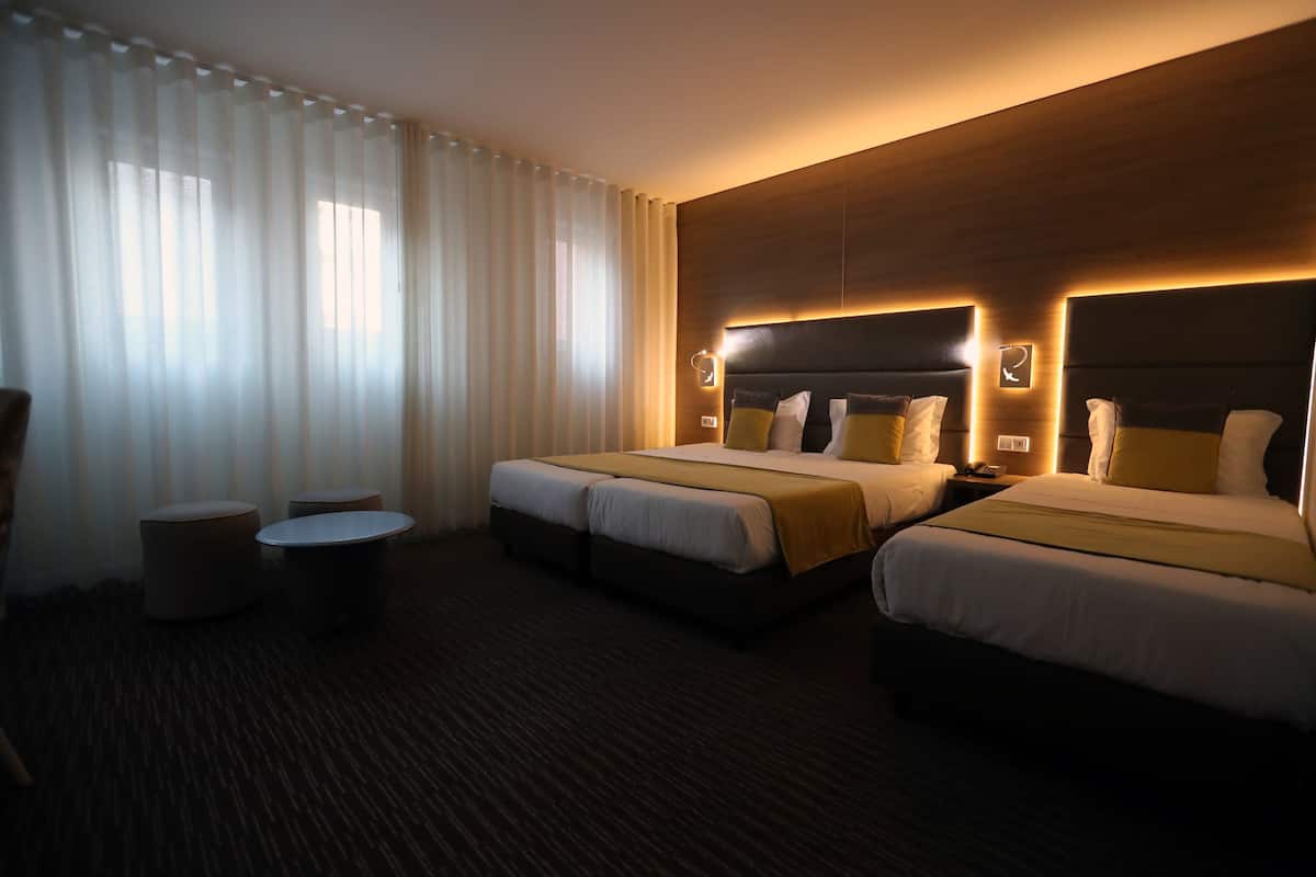 A hotel room with two beds, a small table, and a chair.