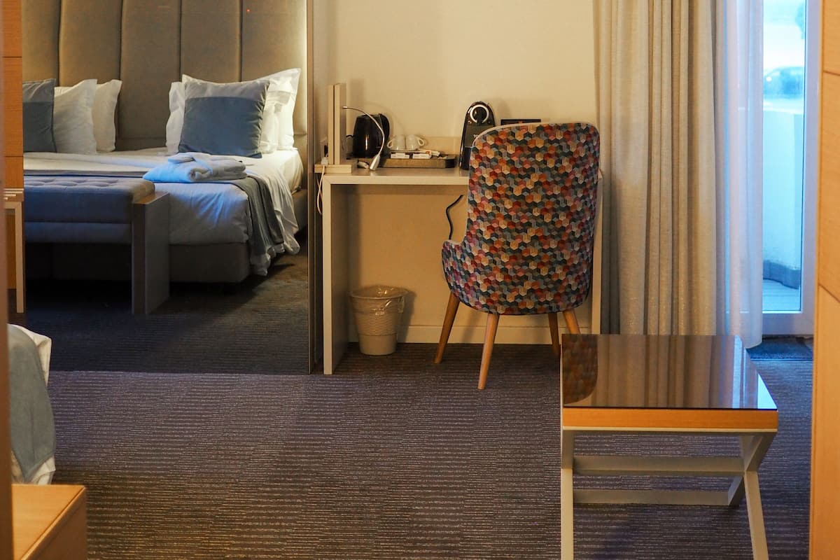 A hotel room with a bed, a desk, a chair, and a small table.