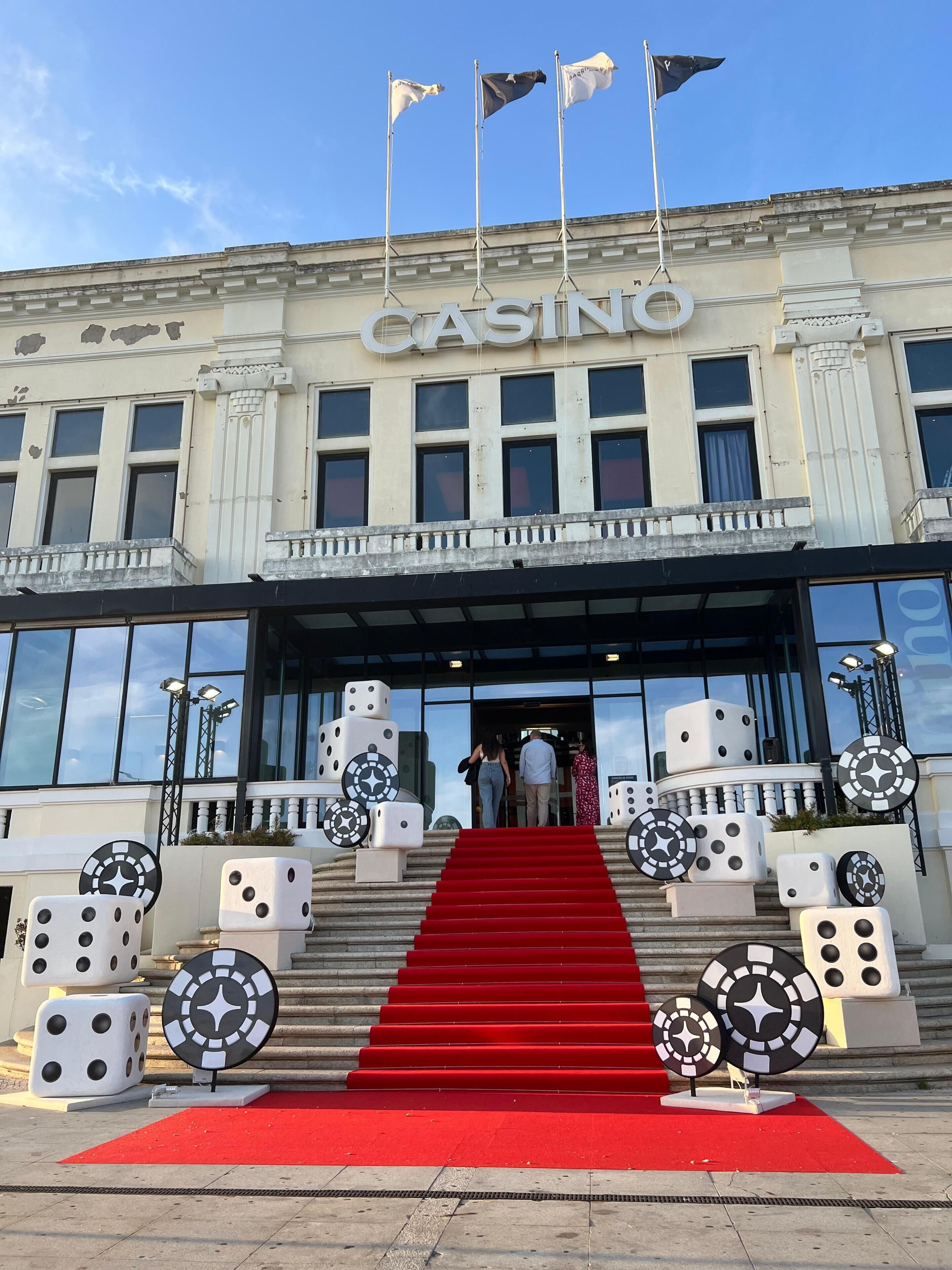 A building with a 'CASINO' sign, a red carpet, and dice sculptures.