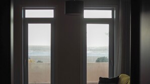 A hotel room with a sofa, a coffee table, and a view of the beach through large windows. -  THE ONE Grand Hotel da Póvoa 4 (Povoa De Varzim)