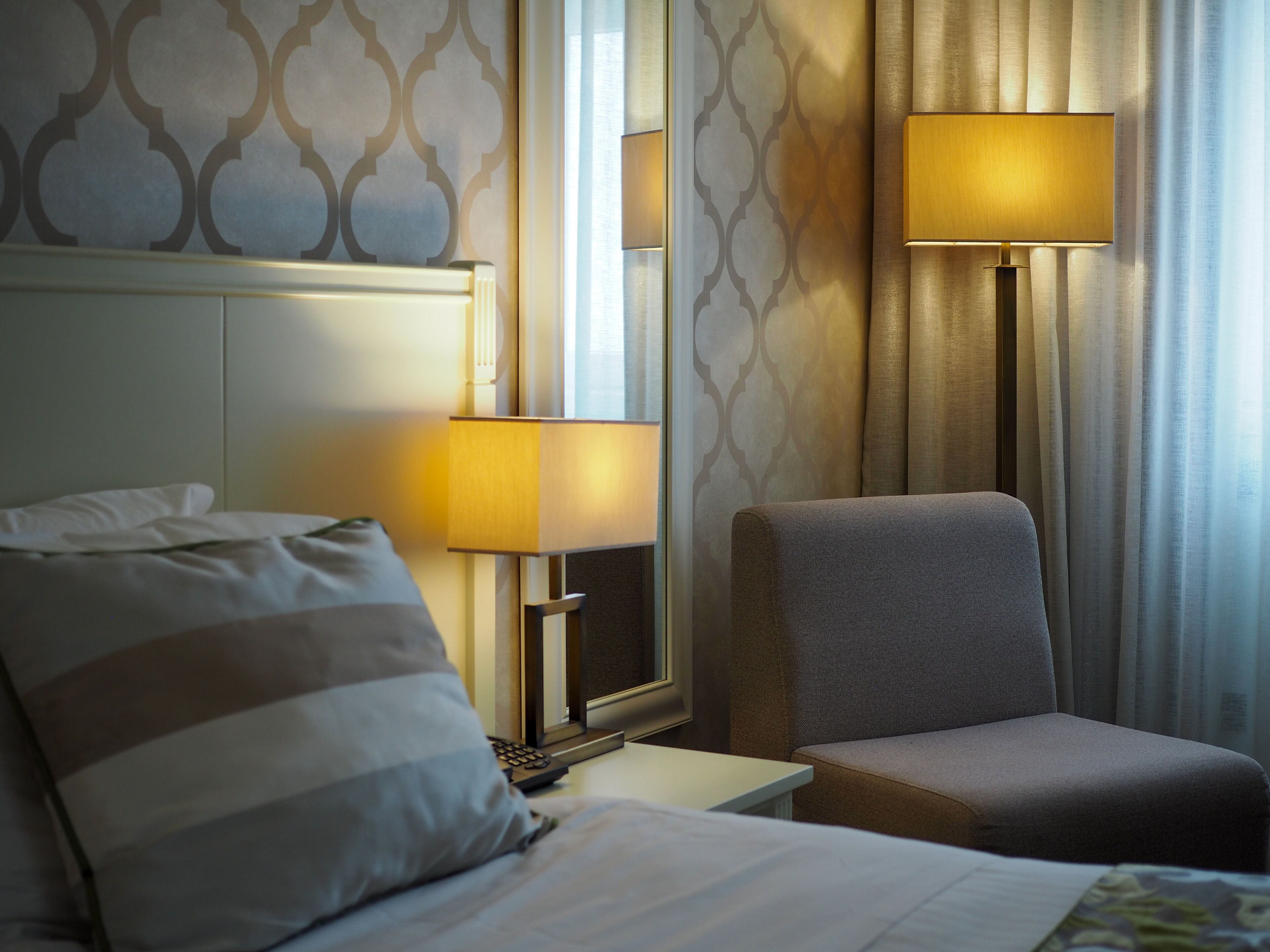 Une chambre d’hôtel avec un lit, deux lampes de chevet, une chaise et une table de chevet.