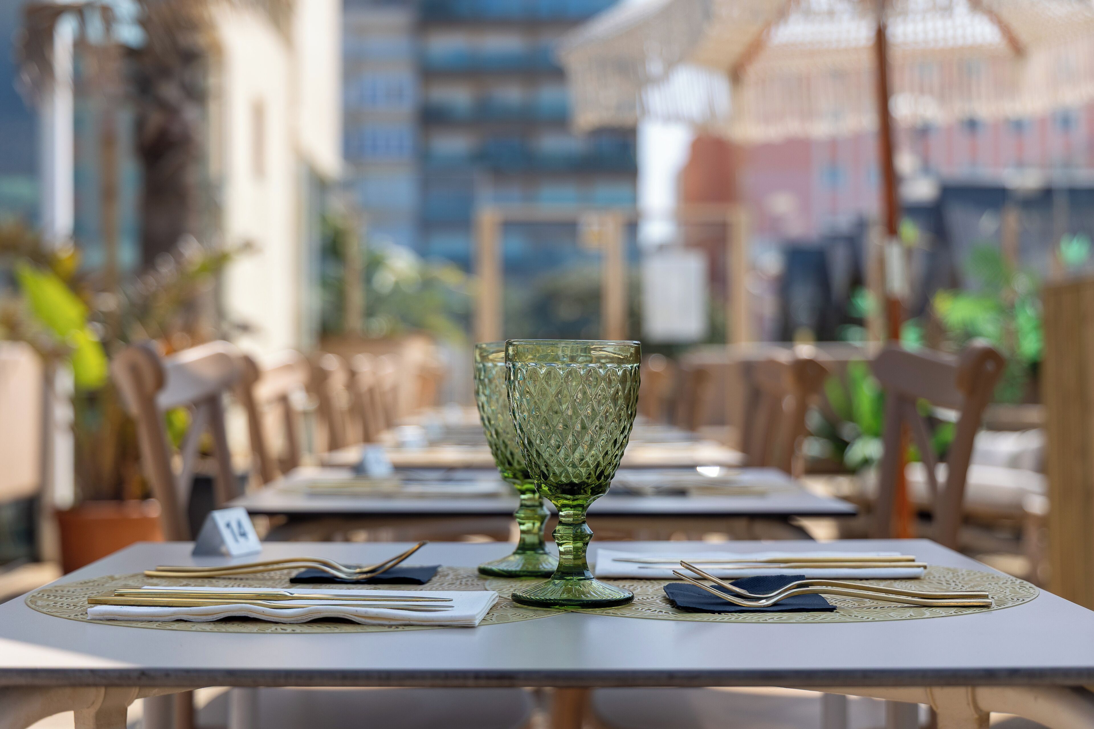 A dining table with a green glass, chopsticks, and a napkin on a placemat.