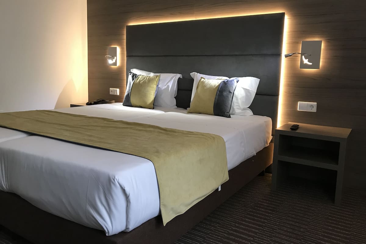 A modern hotel room with a large bed, a bedside table, and a nightstand.