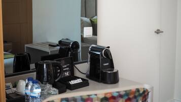 A hotel room with a coffee machine, a water bottle, and a small tray with a card and a coin.