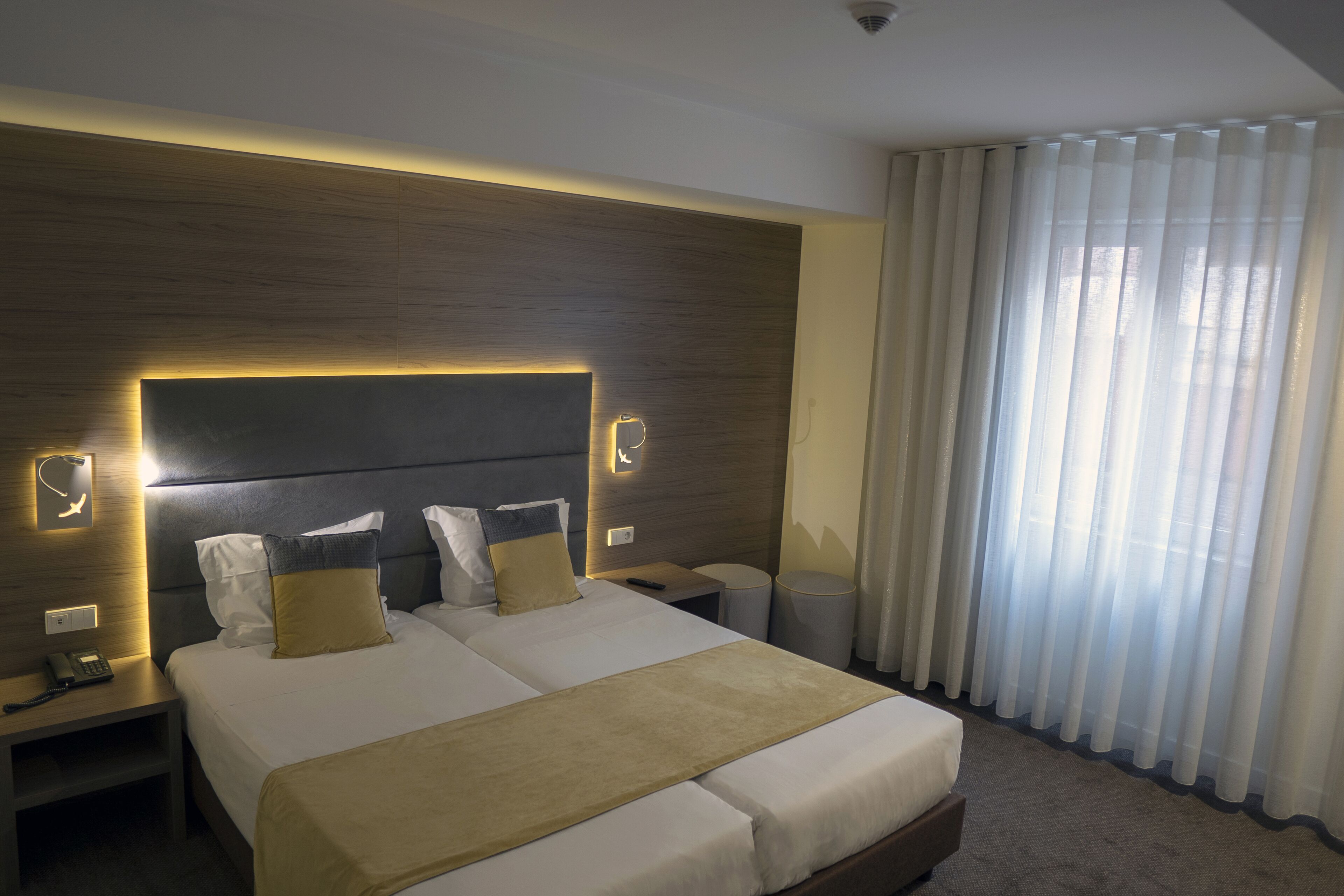 A hotel room with a large bed, bedside tables, a phone, and a window with curtains.