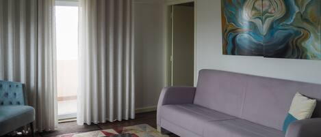 Un salon avec un canapé, un fauteuil, une table basse et un tableau accroché au mur.