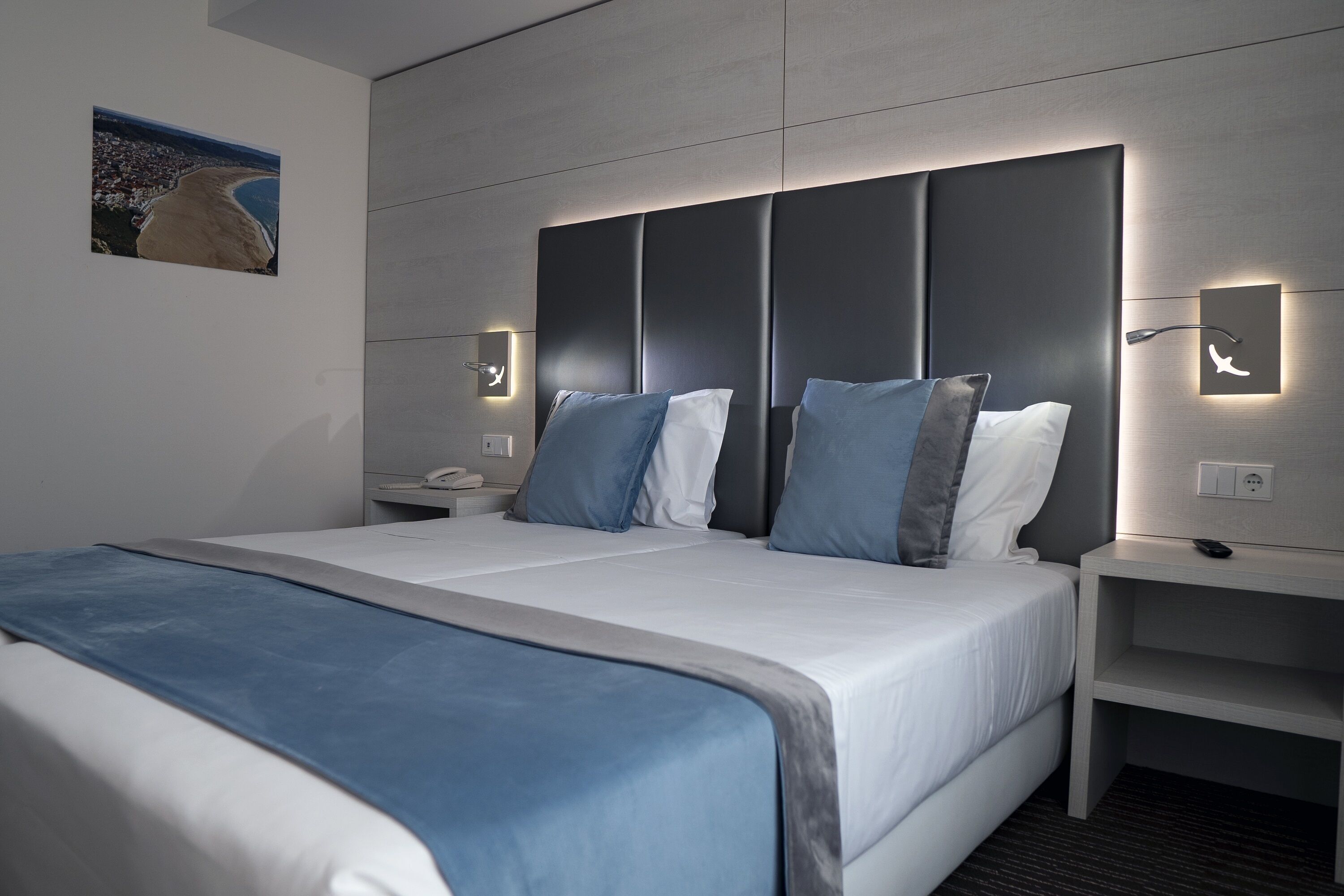 Ett modernt hotellrum med en stor säng, två sängbord och ett litet bord.