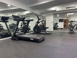 Une salle de sport équipée de tapis de course, de vélos d’appartement et d’appareils de musculation.