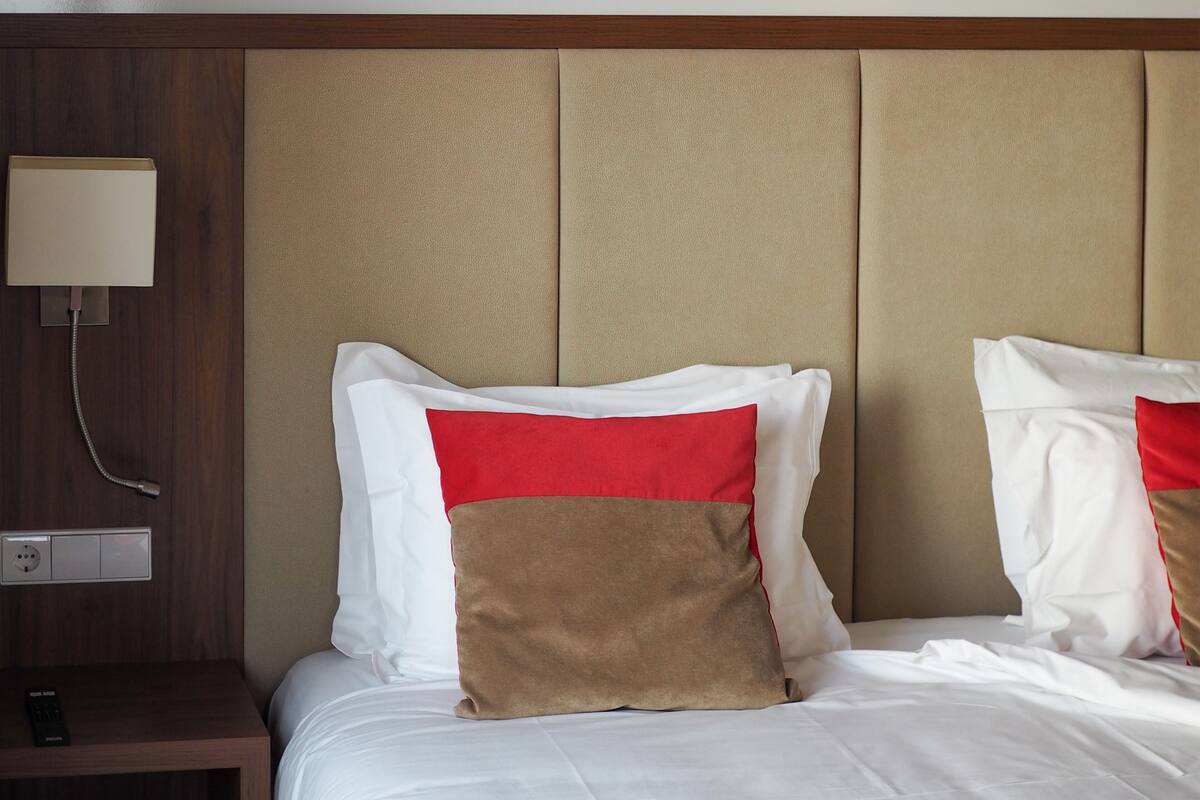 A hotel room with a bed, a nightstand, a lamp, and a telephone.