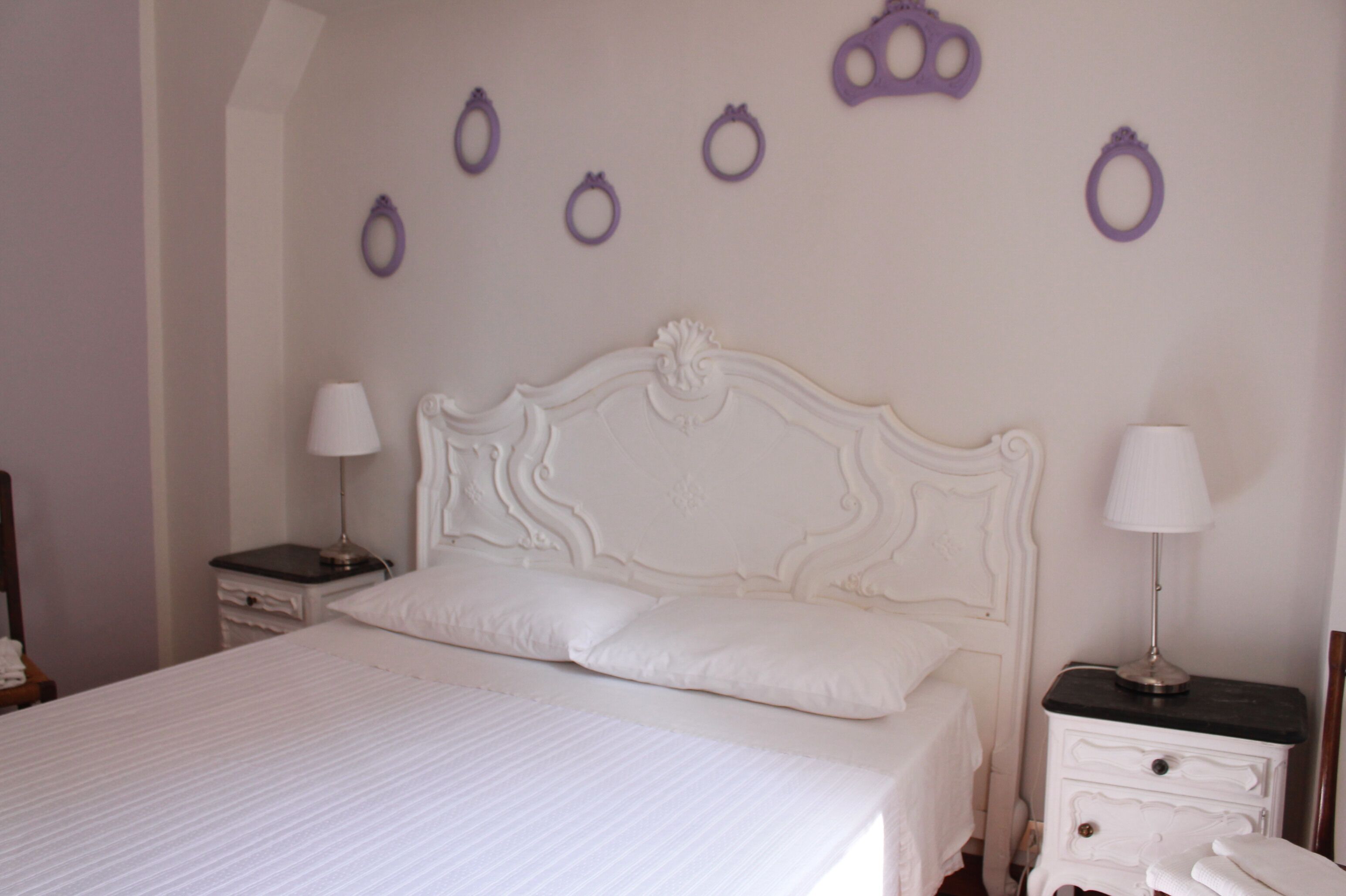 A neatly made bed with a white headboard and two bedside tables with lamps.
