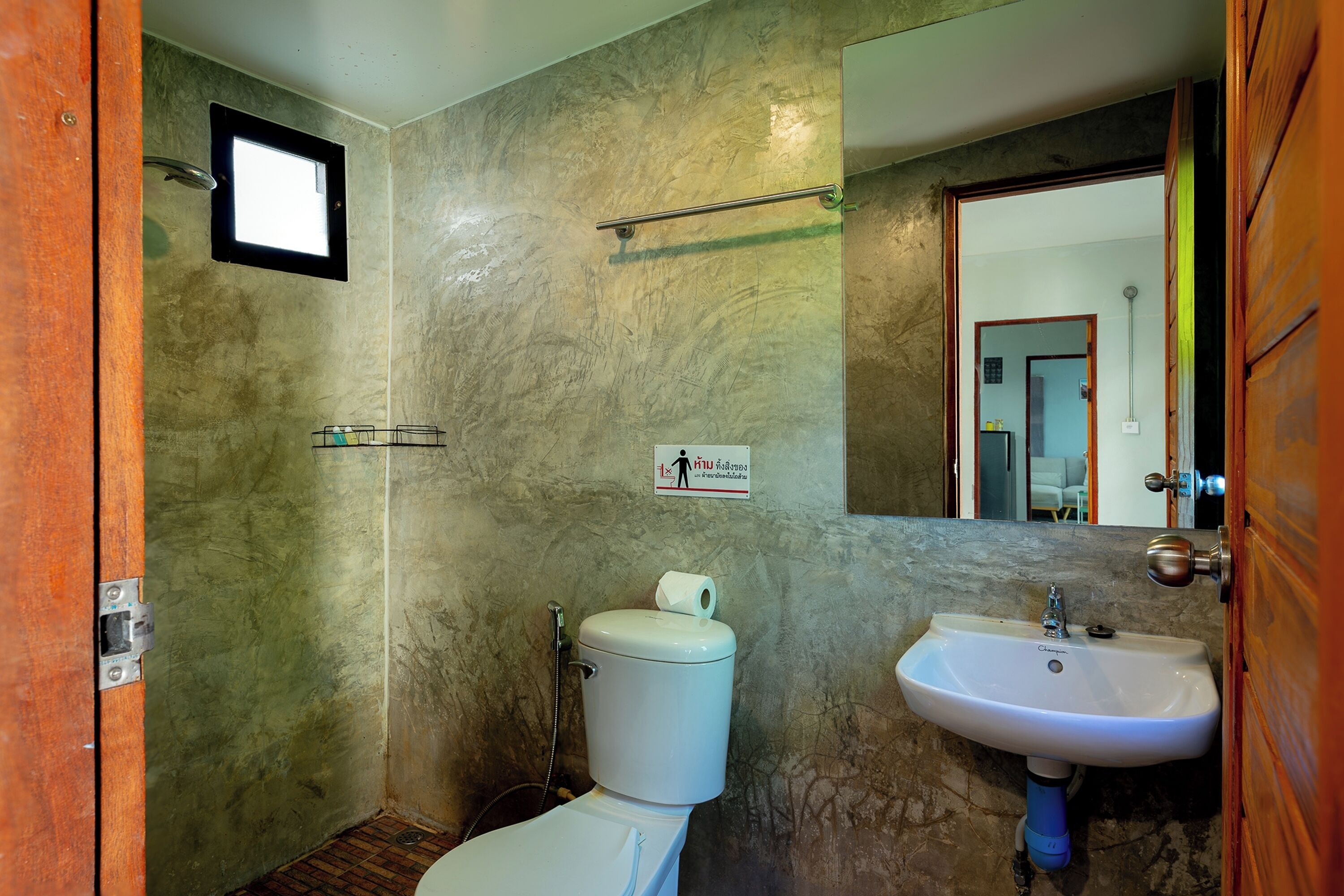 A bathroom with a toilet, sink, shower, and a small window.