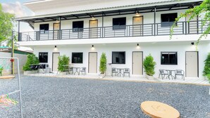 A two-story building with a covered outdoor seating area, multiple doors, and potted plants. - Malinee Resort (Choeng Thale)