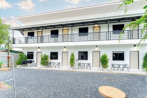 A two-story building with a covered outdoor seating area, multiple doors, and potted plants.