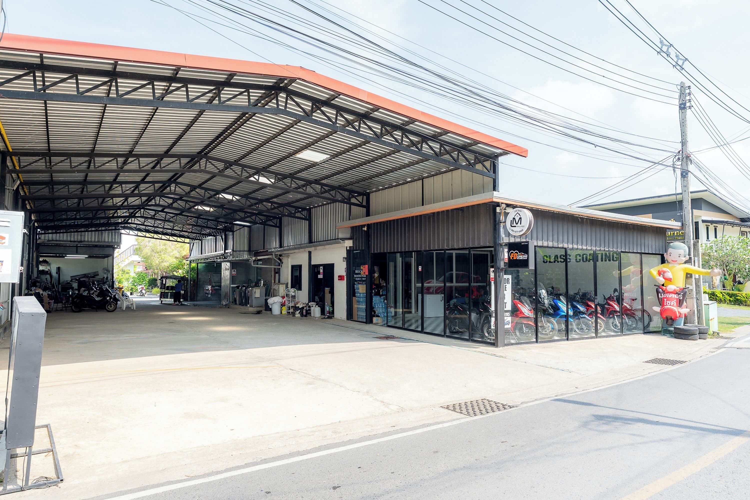 Um posto de combustíveis com área coberta, uma loja de motos e vista livre para a rua.