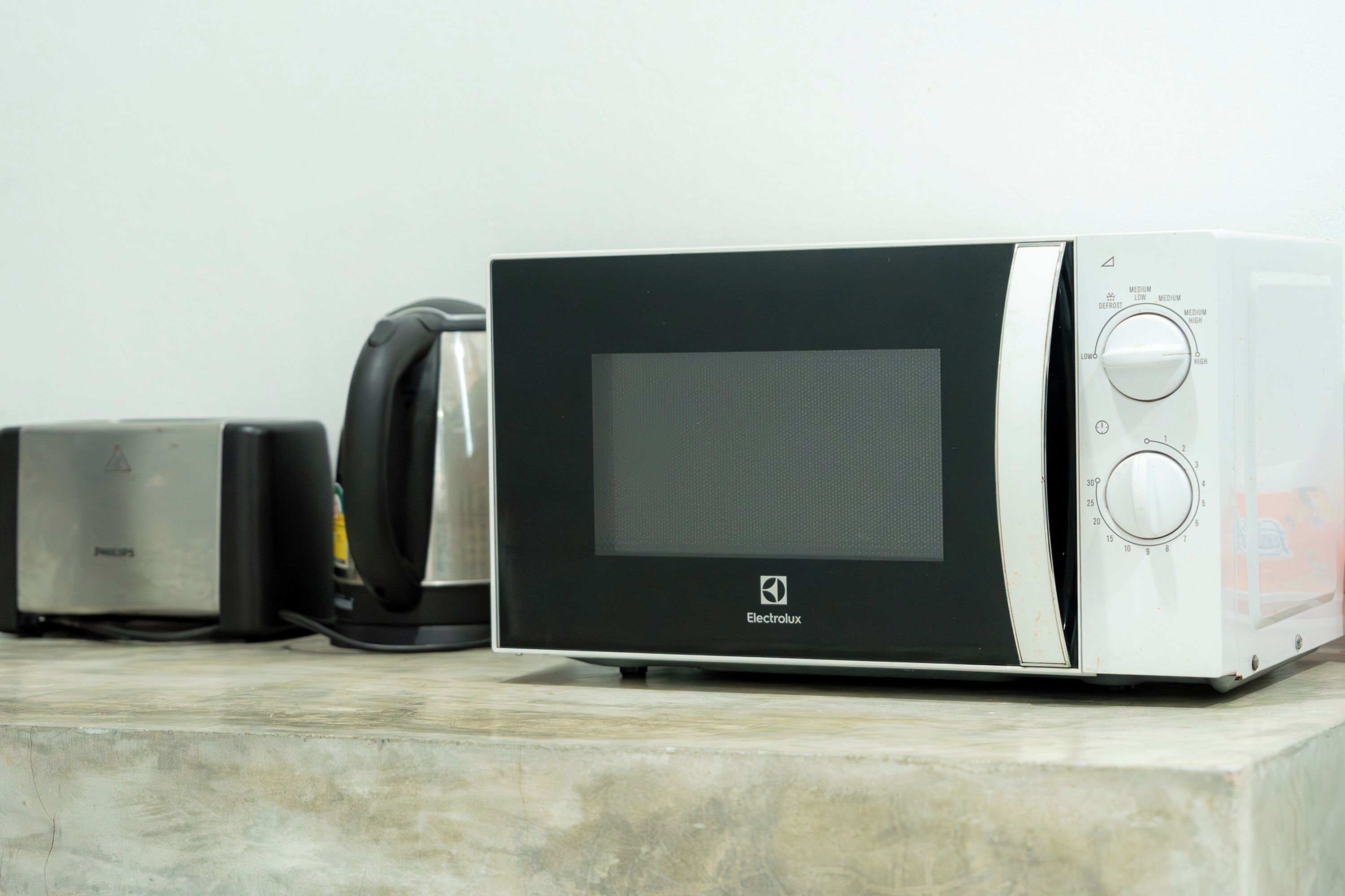 A microwave oven with a digital display and control panel, placed on a marble countertop.