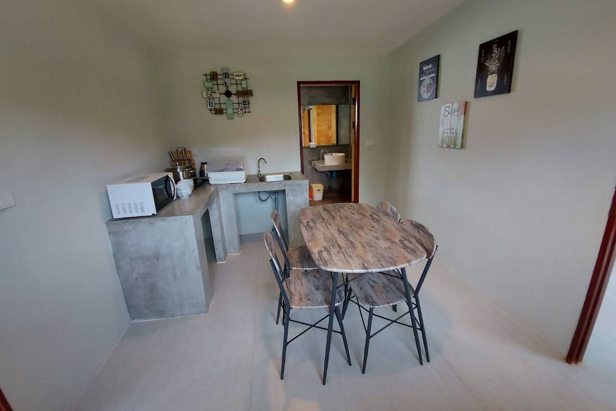 Cozinha compacta com mesa e cadeiras, micro-ondas e pia.