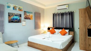 A neatly arranged bedroom with a bed, a small table, a chair, and wall art. - Malinee Resort (Choeng Thale)