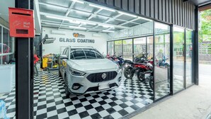 A car wash facility with a glass car wash area, a white car, and various motorcycles. - Malinee Resort (Choeng Thale)