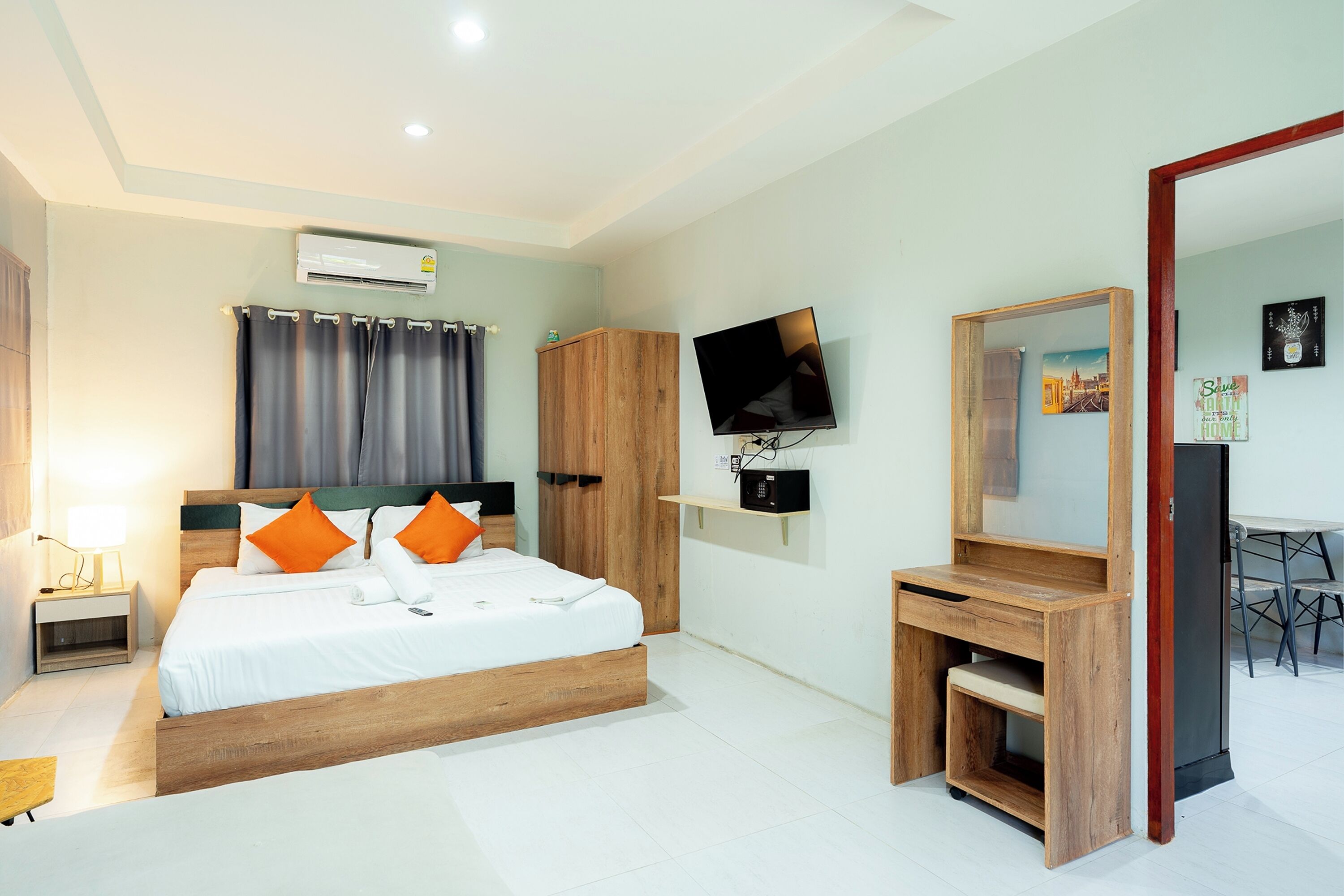 A bedroom with a bed, a TV, a desk, a mirror, and a wardrobe.