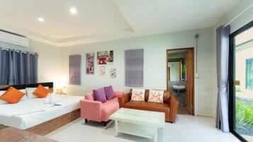 Una habitación de hotel moderna con una cama, dos sofás, una mesa de centro y un baño visible a través de una puerta abierta.