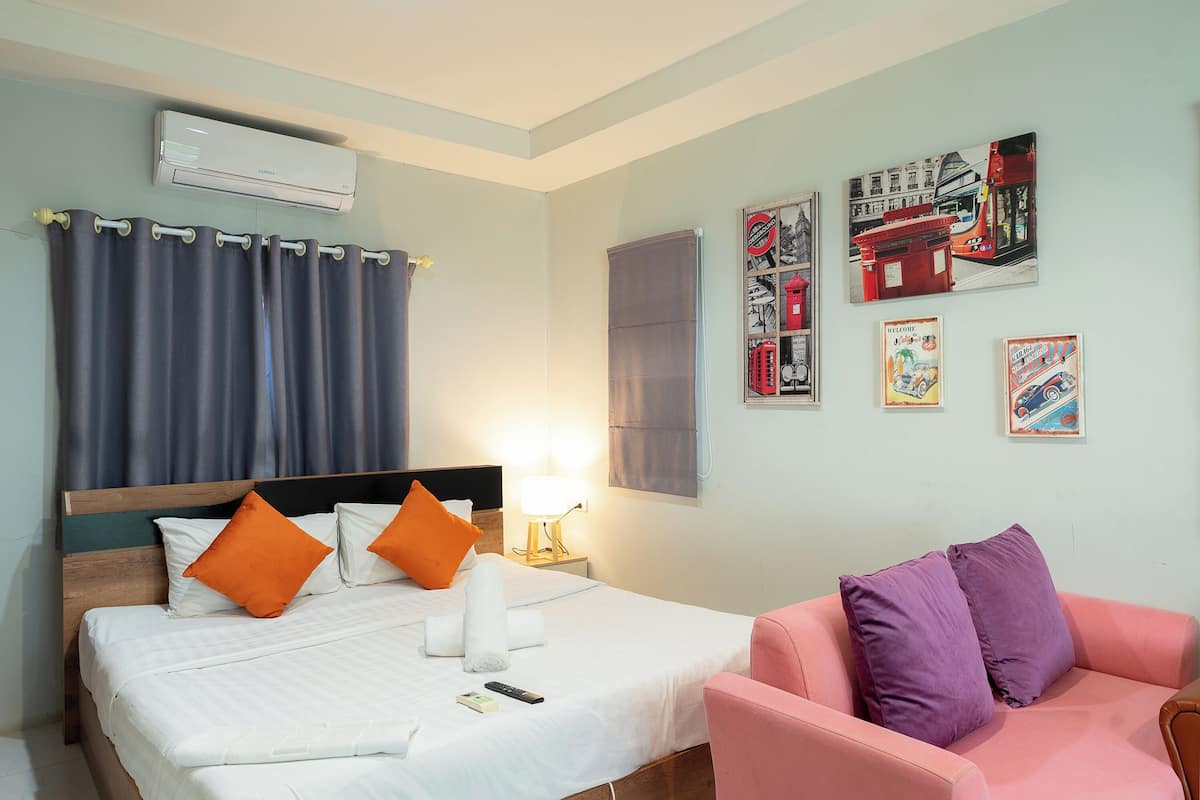 Een hotelkamer met een bed, een stoel, een wandairconditioner en ingelijste foto's.