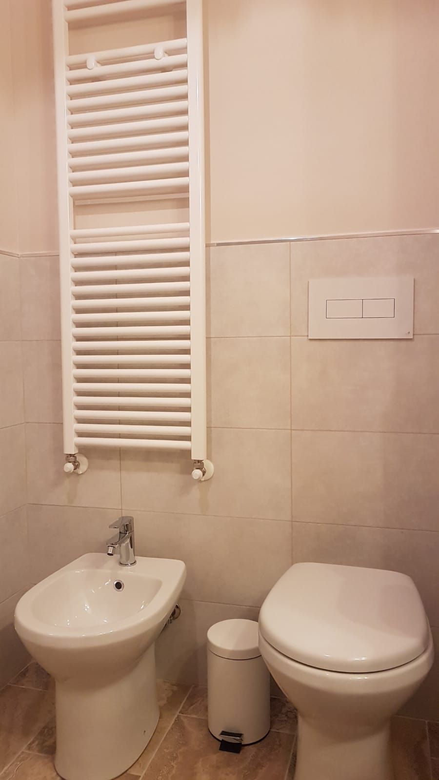 A bathroom with a bidet, a toilet, a sink, and a towel rack.