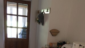 Une cuisine avec une porte en bois, une machine à café et une poubelle.
