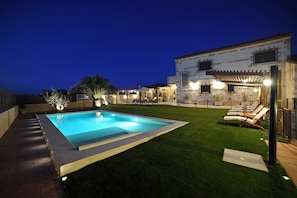 A swimming pool with a surrounding deck, a grassy area, and a building with outdoor seating. - Rural house 5 * Grand Luxury in Toledo, Puy Du Fou (Albarreal de Tajo)
