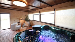 A spa area with a hot tub, wicker furniture, and large windows. - Rural house 5 * Grand Luxury in Toledo, Puy Du Fou (Albarreal de Tajo)