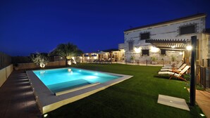 A swimming pool with a surrounding deck, a covered patio area, and a grassy lawn with lounge chairs. - Rural house 5 * Grand Luxury in Toledo, Puy Du Fou (Albarreal de Tajo)