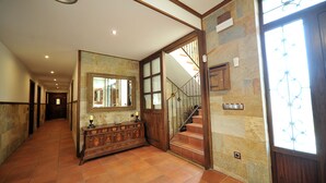 A hallway with a wooden staircase, a large mirror, and a stone wall. - Rural house 5 * Grand Luxury in Toledo, Puy Du Fou (Albarreal de Tajo)