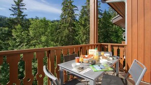 A balcony with a table set for breakfast, surrounded by wooden railings, overlooking a forested area. - Wifi, 50m from ski slopes, tv, ski locker, 31m², Morillon (Morillon)