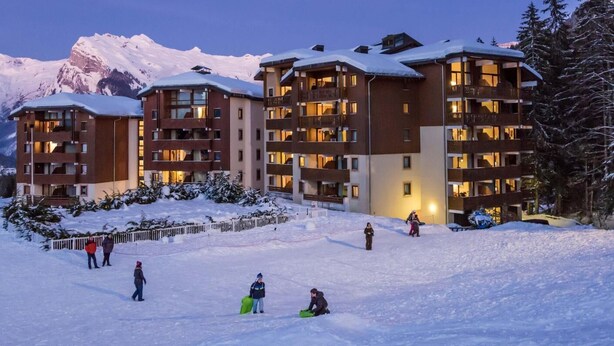 A multi-story hotel with balconies and a ski slope in the foreground.
