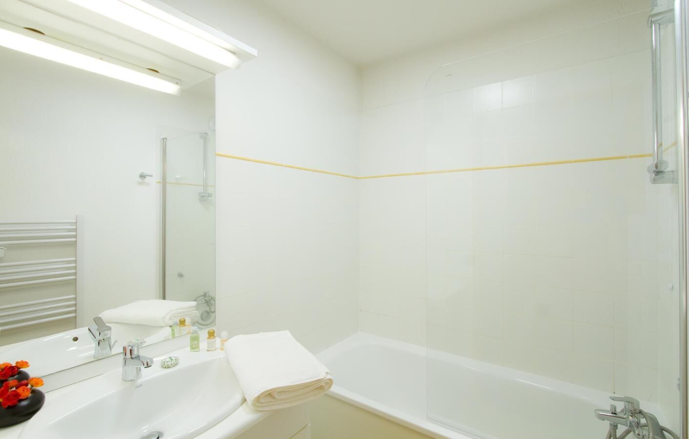 Une salle de bain moderne avec un lavabo blanc, un miroir et une baignoire.