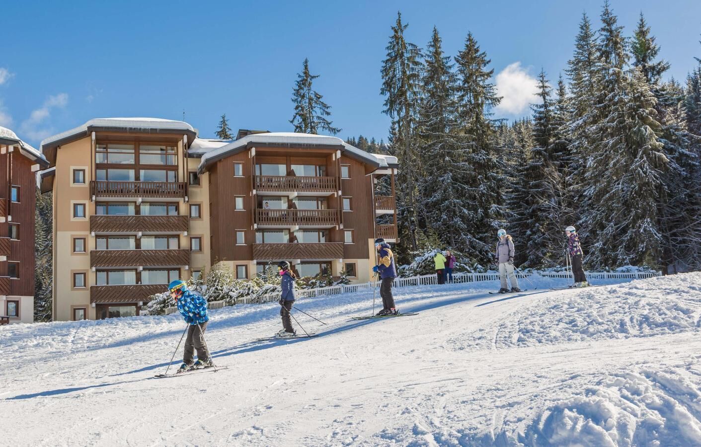 Une station de ski avec des bâtiments à plusieurs étages, des pistes de ski et des arbres couverts de neige.
