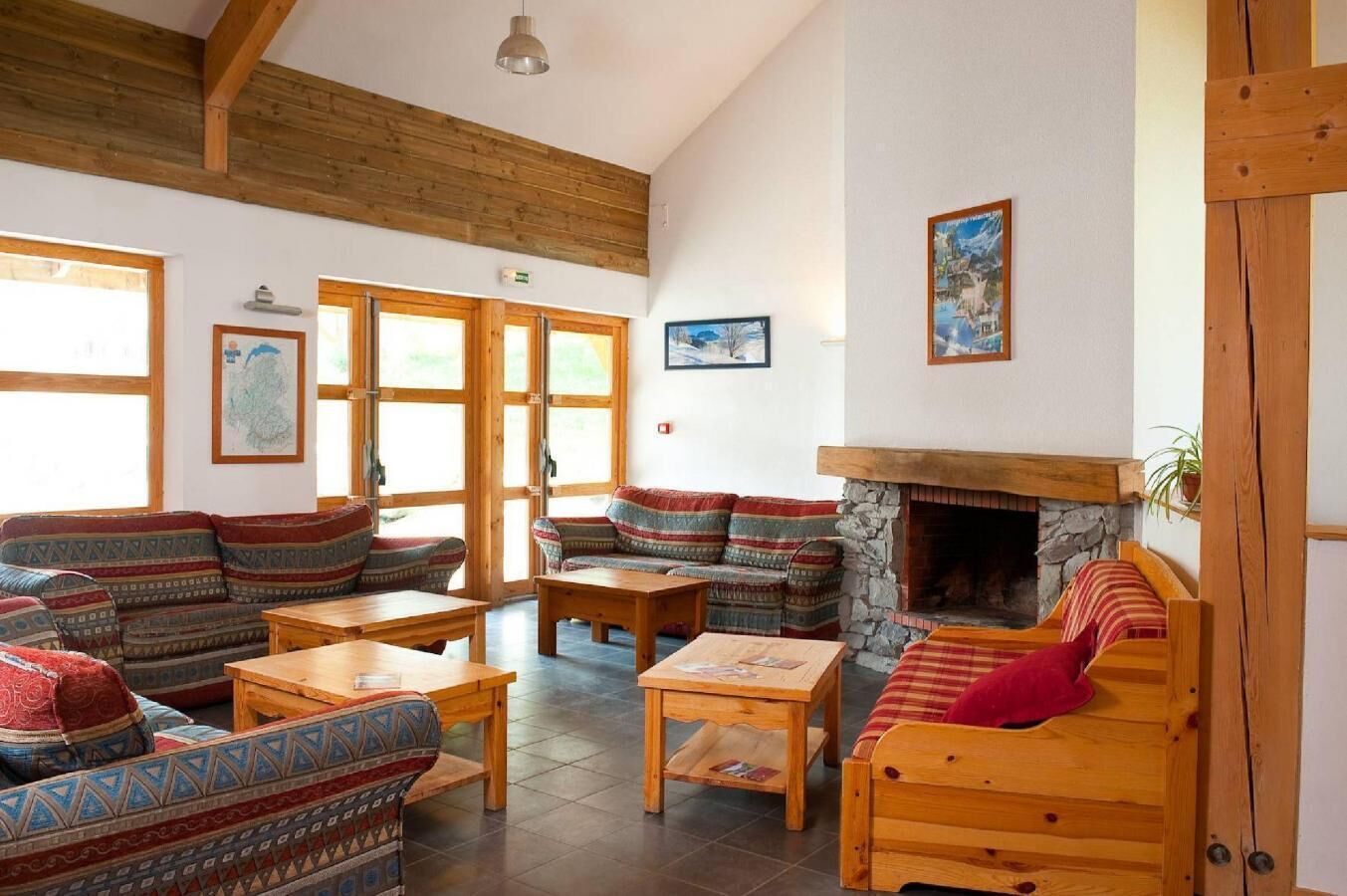 A spacious room with wooden furniture, a stone fireplace, and large windows.