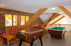 Ein gemütliches Loftzimmer mit Billardtisch, einer Couch und einem kleinen Tisch.