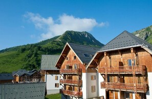 Filetta di chalet in legno con balconi, con montagne sullo sfondo.