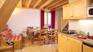 A cozy cabin interior with a dining area, kitchen, and a sleeping area with a bed and a chair. - Wifi, 200m from ski slopes, swimming pool, terrace, balcony, parking, 30-35m², Saint Sorlin d'Arves (Saint-Sorlin-d'Arves)