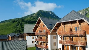 A row of wooden chalets with balconies, set against a backdrop of a mountain and clear sky. - Wifi, 200m from ski slopes, swimming pool, terrace, balcony, parking, 30-35m², Saint Sorlin d'Arves (Saint-Sorlin-d'Arves)