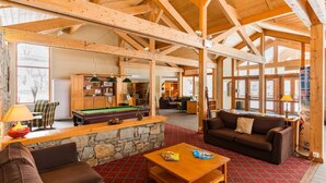 A spacious indoor area with a pool table, a billiards table, and a cozy seating area with a couch and chairs.