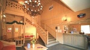 Un intérieur en bois avec un escalier, un comptoir d’accueil et un lustre.
