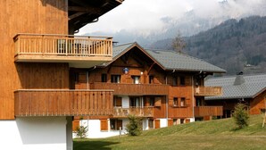 Un bâtiment de style chalet en bois, doté de balcons, avec une enseigne indiquant « La Casa del Vino », et un paysage montagneux en arrière-plan.