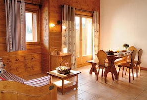 A cozy wooden cabin with a dining area, a sofa, and a table with breakfast items.